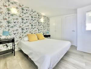 una camera da letto con un letto bianco e carta da parati tropicale di Summer Breeze Penthouse a Puerto de la Cruz