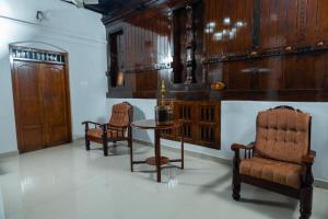 Habitación con 2 sillas, mesa y sillas en Brookside Heritage Resort, en Kumarakom