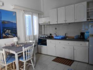 a kitchen with white cabinets and a table and chairs at Meltemia Studios in Marathokampos