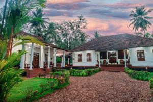 a house with a courtyard and palm trees at Brookside Heritage Resort in Kumarakom