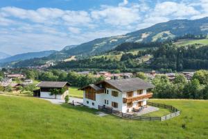 une maison dans un champ avec des montagnes en arrière-plan dans l'établissement Landhaus Geig, à Hopfgarten im Brixental