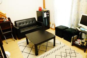 泉佐野的住宿－MINPAKU-P 民泊p，客厅配有黑色真皮沙发和咖啡桌