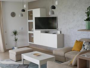 a living room with a tv on a white cabinet at ADELINA Apartman 