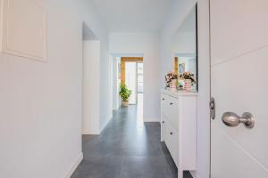 a hallway with white walls and a white cabinet with flowers on it at Casa Rural Duran in Mocejón