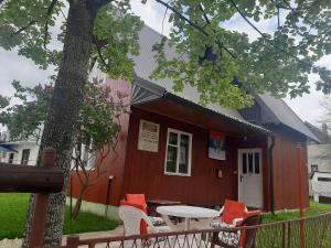 un edificio rosso con un tavolo e sedie di fronte di Guesthouse Durmitor Magic a Žabljak