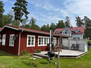 a red cottage with a deck and a grill at Luxury cosy cottage by the sea in Karlstad