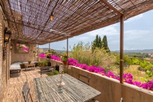 eine Außenterrasse mit einem Tisch und lila Blumen in der Unterkunft Casa rural siglo xviii in Pals