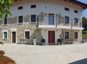 una casa in pietra con porta rossa e balcone di Casa21 a SantʼAntonio Tortal