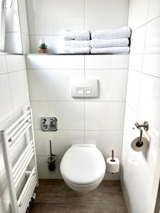 a white bathroom with a toilet and towels at Prime Host Balcony Apartment in Karlsruhe