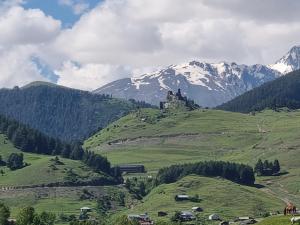 un castillo en la cima de una colina verde con montañas en Guest House Mirgvela en Omalo
