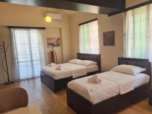 two beds in a room with windows at VILA 32 in Berat