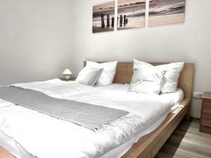 - une chambre dotée d'un grand lit avec des draps et des oreillers blancs dans l'établissement *Schwarzwald-Apartment 1° *, à Elzach