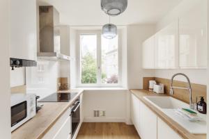 eine weiße Küche mit Spüle und Fenster in der Unterkunft Le Nuage Malouin - Appt à 300m de la plage in Saint-Malo