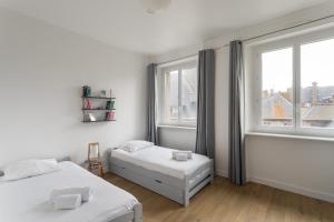 ein weißes Schlafzimmer mit zwei Betten und einem Fenster in der Unterkunft Le Nuage Malouin - Appt à 300m de la plage in Saint-Malo