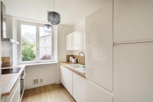 eine weiße Küche mit Spüle und Fenster in der Unterkunft Le Nuage Malouin - Appt à 300m de la plage in Saint-Malo