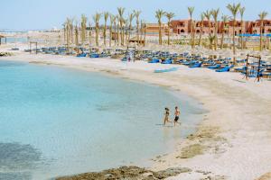 twee mensen lopen op het strand bij de oceaan bij Pickalbatros Villaggio Aqua Park - Portofino Marsa Alam in Marsa Alam