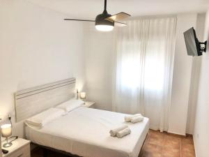 a white bedroom with a bed with towels on it at Alhattic in Alhaurín el Grande