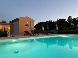 a swimming pool with chairs and umbrellas next to a house at MARIS Apartments & Bedrooms in Alghero