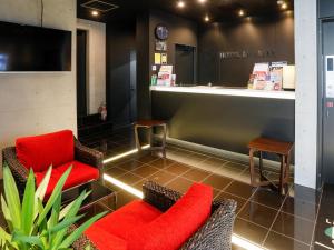 HOTEL LiVEMAX Higashi Ginza في طوكيو: غرفة انتظار مع كراسي حمراء وكاونتر