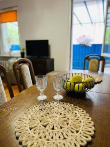- une table en bois avec un bol de fruits et deux verres dans l'établissement Nowomiejska Blisko Centrum, à Suwałki