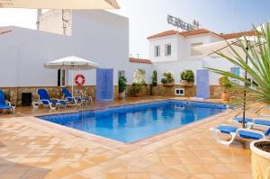 a pool in a hotel with chairs and an umbrella at Hostal Manolo in Garrucha