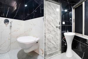 a bathroom with a toilet and a glass shower at FabHotel Magnus in Surat