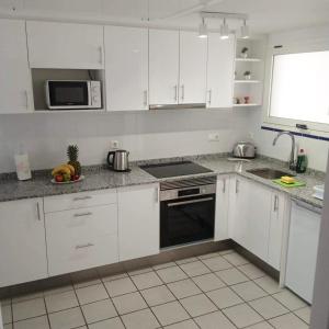 a kitchen with white cabinets and a stove top oven at Casa Monet - La Calma - 4 pools- Big terrace - Orihuela Costa in Playa Flamenca
