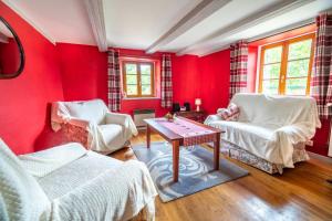 Sala de estar de color rojo con 2 sillas y mesa en La Ferme du Grand Père Prosper, en Liézey