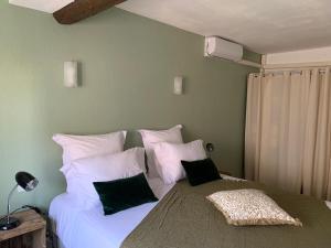 um quarto com uma grande cama branca com almofadas pretas em La flemme en rose em Aigues-Mortes