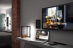 a laptop on a desk with a tv and wine glasses at Aparthotel Mittermeiers Alter Ego in Rothenburg ob der Tauber