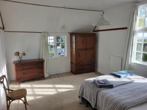 um quarto com uma cama, uma cómoda e janelas em 1920s Classic Cozy 2-Bedroom Villa Apartment in Parnell em Auckland