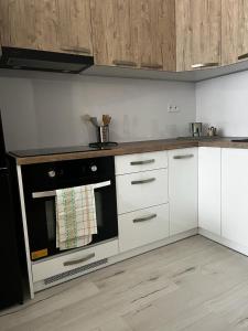 eine Küche mit weißen Schränken und einem schwarzen Backofen in der Unterkunft Apartmán Lúčky Bojnice in Bojnice