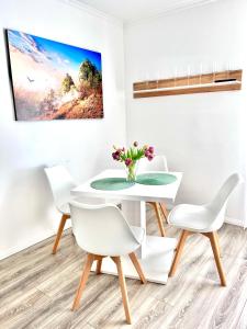 ein weißes Esszimmer mit einem Tisch und Stühlen in der Unterkunft Prime Host Balcony Apartment in Karlsruhe