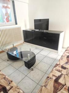 ein Wohnzimmer mit einem TV und einem Couchtisch aus Glas in der Unterkunft 3 rue Maurice Utrillo in Bourg-en-Bresse
