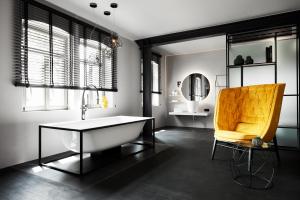 a bathroom with a tub and a yellow chair at Mittermeiers Alter Ego in Rothenburg ob der Tauber