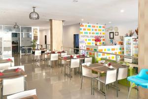 a restaurant with tables and chairs and a kitchen at Urbanview Hotel Mulia Indah Palopo in Palopo