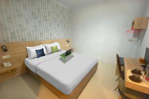 a bed in a room with a desk and a bed sidx sidx sidx at Urbanview Hotel Mulia Indah Palopo in Palopo