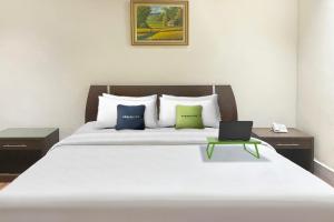 a bedroom with a bed with a laptop on it at Urbanview Hotel Mulia Indah Palopo in Palopo
