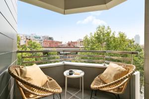 uma varanda com 2 cadeiras de vime e uma mesa em Sardenya Apartment by Olala Homes em Barcelona