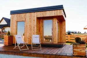 a wooden cabin with two chairs on a deck at Osada Dursztyn- Przystanek Podhale in Białka Tatrzańska