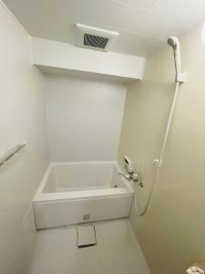 La salle de bains est pourvue d'une douche et d'une baignoire. dans l'établissement ASUKA HINODECHO ｌ日の出町, à Kusugaurachō
