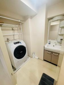 uma casa de banho com uma máquina de lavar roupa e um lavatório em ASUKA HINODECHO ｌ日の出町 em Kusugaurachō