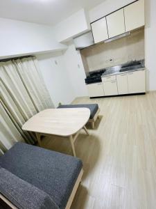 une chambre avec une table et des chaises ainsi qu'une cuisine dans l'établissement ASUKA HINODECHO ｌ日の出町, à Kusugaurachō