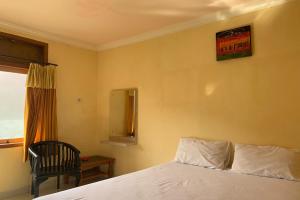 sypialnia z łóżkiem, krzesłem i oknem w obiekcie OYO 92775 Wisma Phinisi Syariah 