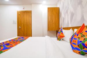 1 dormitorio con cama blanca y almohadas coloridas en FabHotel Woodlark Inn, en Indore