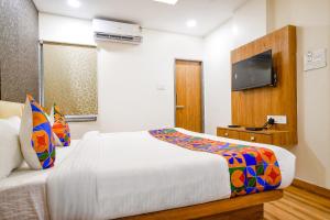 1 dormitorio con 1 cama y TV de pantalla plana en FabHotel Woodlark Inn, en Indore