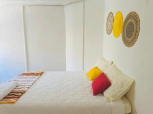a white bed with colorful pillows on top of it at Takasira Appart Hotel centre ville in Fort Dauphin