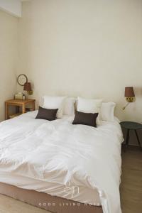 uma cama grande com lençóis brancos e almofadas em 瀉湖-私人公寓 The Lagoon-Mediterranean vibe vacation house em Kaohsiung