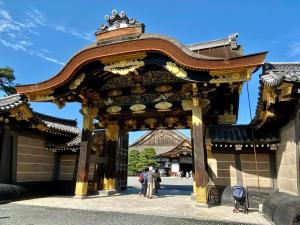 a gate to a building with people standing under it at Kyoto Uraraka Guest House in Kyoto