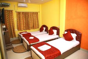 a room with two beds with red and white sheets at Babul Hotel in Kolkata